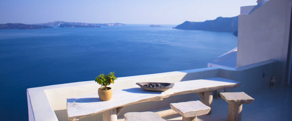A table with a plant and bowl on it overlooking the ocean.